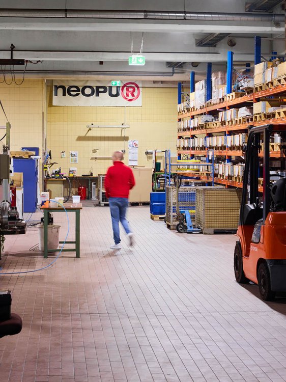 Produktionshalle mit Lagerregalen, Gabelstapler und Mitarbeiter im Betrieb