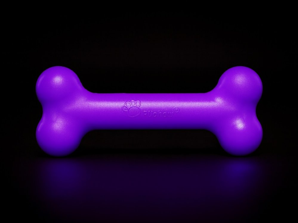 Lila PUchew Hundekauspielzeug in Knochenform vor schwarzem Hintergrund